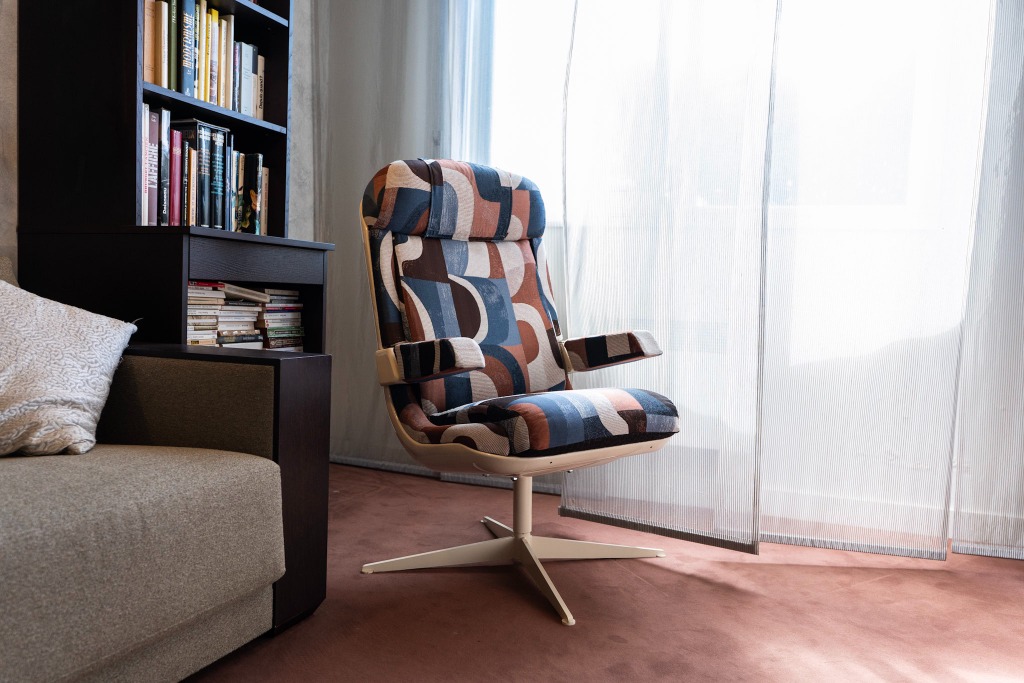 Fauteuil Ticquai à motif graphique dans un salon, près d’une bibliothèque et d’un voilage